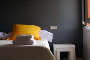 a room with a bed with a yellow pillow and a table at Hostal Totsompops in Colera