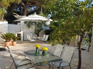 BnB Villa Sant'Angelo في جينوسا مارينا: طاولة عليها كراسي وطاولة عليها زهور