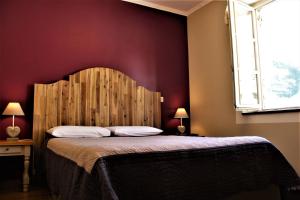 Schlafzimmer mit einem großen Bett mit einem Kopfteil aus Holz in der Unterkunft Hôtel BURLATIS in Sainte-Énimie