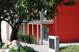 ein rotes Gebäude mit einem TV vor einem Baum in der Unterkunft B&B Lupo in Cavareno