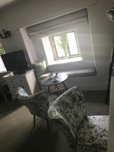 een woonkamer met 2 stoelen, een tafel en een raam bij The Great House Hotel in Bridgend
