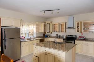モンテゴ・ベイにあるThe Royal Kensington Villa 4の白いキャビネットとステンレス製の冷蔵庫を備えたキッチン