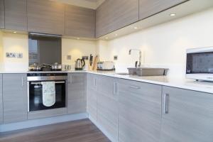 a kitchen with gray cabinets and a sink at Exquisite & Homely Penthouse, 2 mins walk from Cambridge Station, Big balcony, lift access, secured gated on-site parking, self check-in & SUPER Fast WIFI in Cambridge