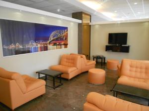 a waiting room with orange chairs and a flat screen tv at Hotel Le Dune in Licola