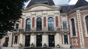 - un grand bâtiment en briques avec un balcon dans l'établissement Apt 5 du Temple HyperCentre & Parking, à Cambrai