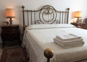 sypialnia z białym łóżkiem z 2 lampami i ręcznikami w obiekcie B&B Pergolesi w Weronie