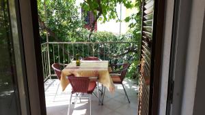 a table and chairs on a balcony with a window at Valun Seaside Apartments in Valun
