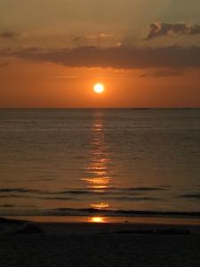 a sunset on the beach with the sun setting at Nas Villaria Langkawi in Pantai Cenang