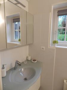 Baño blanco con lavabo y espejo en Le Pressoir, en Beuvron-en-Auge