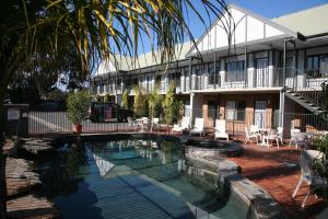 
a hotel room with a pool and lawn chairs at Ibis Styles Adelaide Manor in Adelaide
