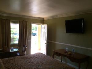 um quarto com uma cama e uma televisão na parede em Santa Ana Travel Inn em Santa Ana