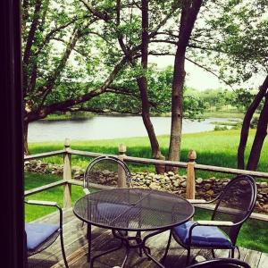 a table and chairs on a deck with a view of a lake at Inn at Fox Hill Farm in Pomfret