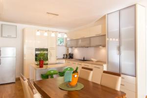 a kitchen with a wooden table and a refrigerator at Lux Apartman Sofia in Sveti Stefan