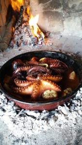 a skillet filled with octopus cooking over a fire at Robinson house Kata in Milna