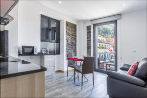 a kitchen and living room with a table and a couch at Enxurros House in Ponta Delgada