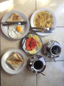 a table with plates of breakfast food and cups of coffee at Batan Duren House in Ubud