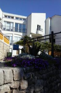 a retaining wall with purple flowers in front of a building at Apartmani Marić in Selce