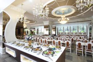 a dining room with a long table with chairs and chandeliers at Royal Benja Hotel - Big Room Family-Friendly in Bangkok