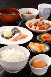 una mesa con platos de comida y tazones de comida en Kurume Hotel Esprit en Kurume