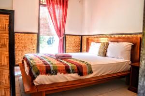 a bedroom with a wooden bed with a window at Padangbai Beach Homestay in Padangbai