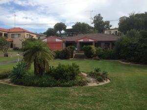 a house with a green yard with a palm tree at Beautiful, Peaceful Estuary Views, Five Star Quality in Dawesville