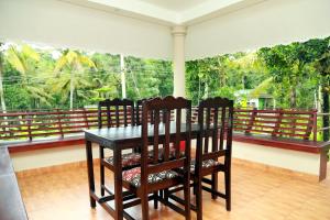 a dining room with a table and chairs on a balcony at Ferndale Homestay in Thekkady
