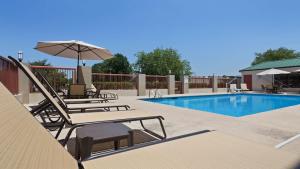 a pool with two lounge chairs and an umbrella at Best Western Lumberton in Lumberton