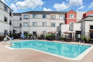 a pool in front of a building with tables and chairs at Hyatt House Morristown in Morristown