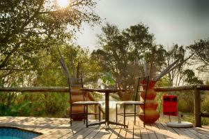 einen Tisch und Stühle auf einer Terrasse mit Pool in der Unterkunft The Old House in Kasane
