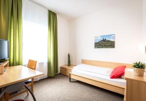 a bedroom with a bed and a desk and a television at Hotel an der Burg in Gießen