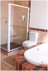 a bathroom with a toilet and a shower and a sink at Asante Guest House in Vanderbijlpark