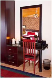 a desk with a red chair and a mirror at Asante Guest House in Vanderbijlpark