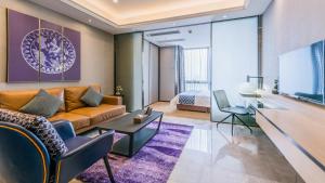 ein Wohnzimmer mit einem Sofa und einem TV in der Unterkunft NOMO Beijing Rd A Jiedeng Mix International Apartment in Guangzhou