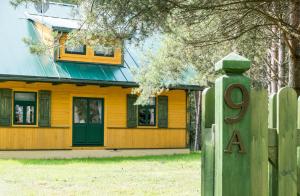 een geel huis met een groene deur en een hek bij Willa Gruszki in Narewka