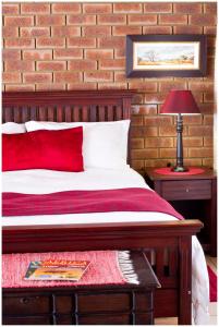 a bedroom with a bed with a red pillow and a lamp at Asante Guest House in Vanderbijlpark