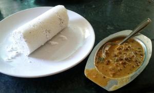a piece of cake on a plate with a cup of soup at Green Garden Deluxe Room in Vayittiri