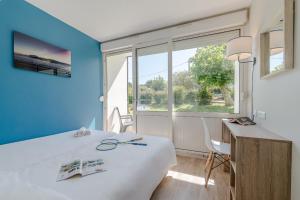 ein Zimmer mit einem Bett und einem Schreibtisch und einem Fenster in der Unterkunft Village Vacances Azureva Anglet in Anglet