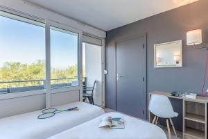 ein Zimmer mit zwei Betten und einem Schreibtisch und einem Fenster in der Unterkunft Village Vacances Azureva Anglet in Anglet