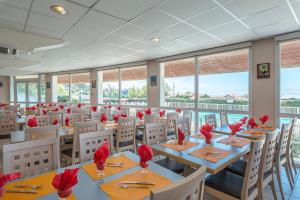 ein Restaurant mit Tischen und Stühlen mit roten Blumen darauf in der Unterkunft Village Vacances Azureva Anglet in Anglet