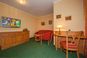 a hotel room with a desk and chairs and a television at Gästehaus Lärchenhang in Mittenwald