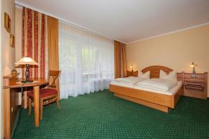 1 dormitorio con cama, escritorio y ventana en Gästehaus Lärchenhang en Mittenwald