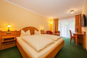 Habitación de hotel con cama, escritorio y mesa. en Gästehaus Lärchenhang, en Mittenwald