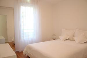 a white bedroom with a large white bed and a window at Residence Art Split in Podstrana