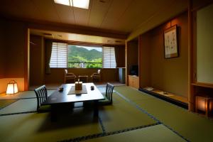 une chambre avec une table, des chaises et une fenêtre dans l'établissement Wakamatsuya, à Zao Onsen