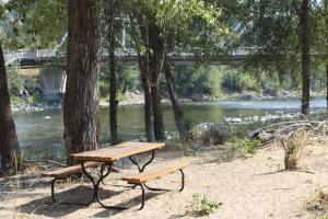 a picnic table and a bench next to a river at Methow River Lodge in Winthrop