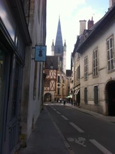 an empty street with a clock on the side of a building at Le Nid De La Chouette in Dijon