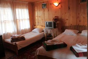 duas camas num quarto com uma televisão na parede em Guest House Polah Ot Minaloto em Zheravna