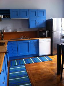 La cuisine est équipée de placards bleus et d'un réfrigérateur en acier inoxydable. dans l'établissement Le Nid De La Chouette, à Dijon