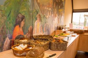 a buffet with baskets of bread and a painting on the wall at Fletcher Hotel-Restaurant Langewold in Roden