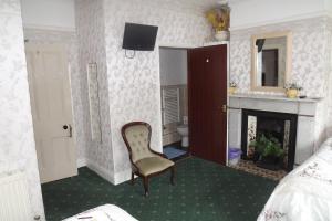 a bedroom with a chair and a fireplace at Hillcrest Guest House in Llangollen